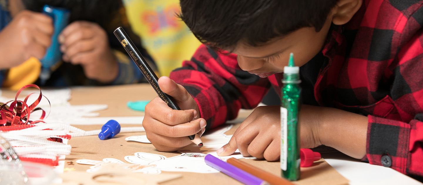 Boy concentrating on craft, pencil in hand.