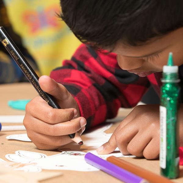 Boy concentrating on craft, pencil in hand.