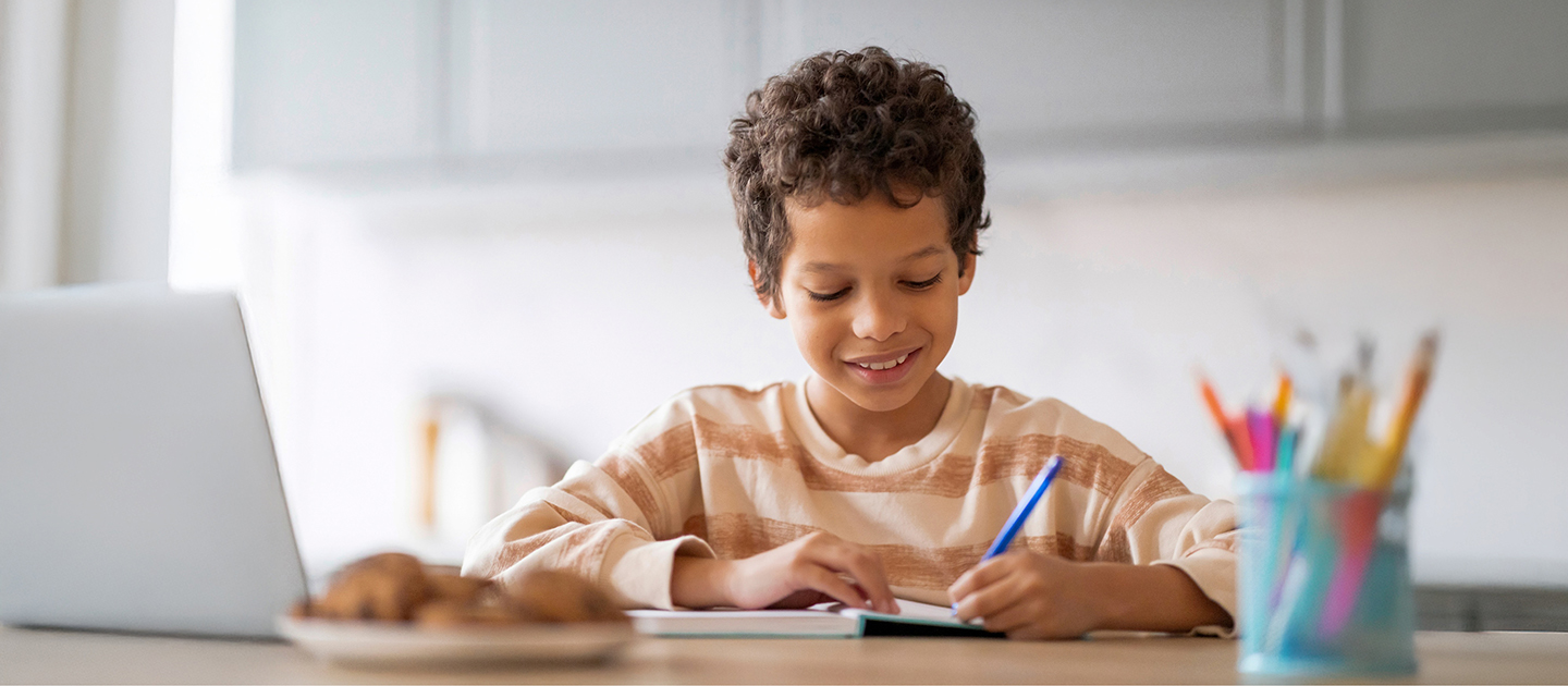 Young boy writing in a notebook. 