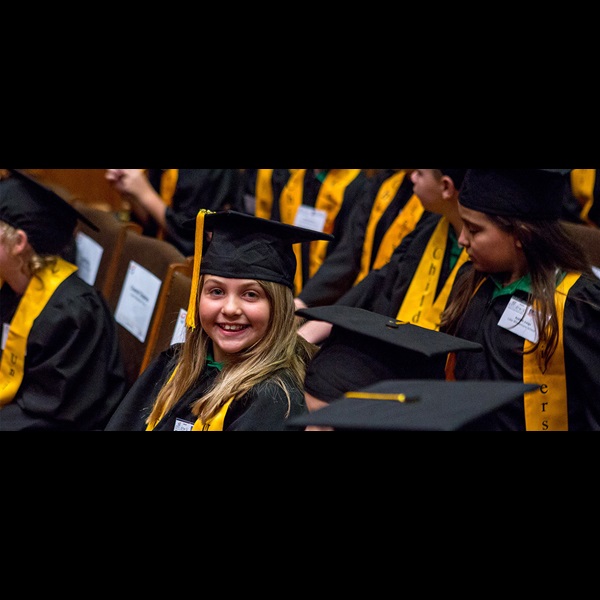 Children in university graduation gowns