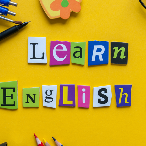 Cut out lettering saying Learn English, surrounded by stationery and on a yellow background.