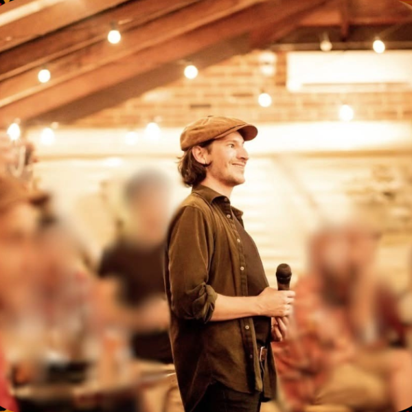 Photo of Dr Christian Mauri holding a microphone and hosting a community event, surrounded by pattern of collage people.