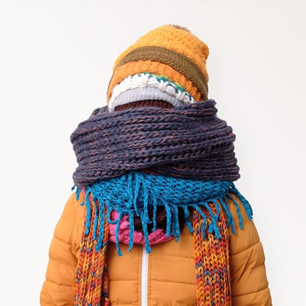 Man bundled up in a coloured jacket with multiple scarves and hats.