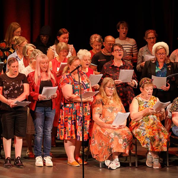 Participants in the Noongar Carols concert 2024 singing on stage with Gina Williams-Ghouse.