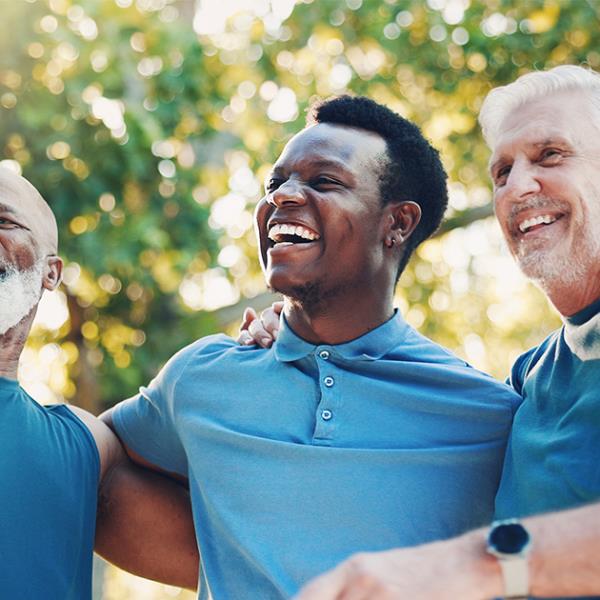 Senior men in blue shirts standing together in a park.