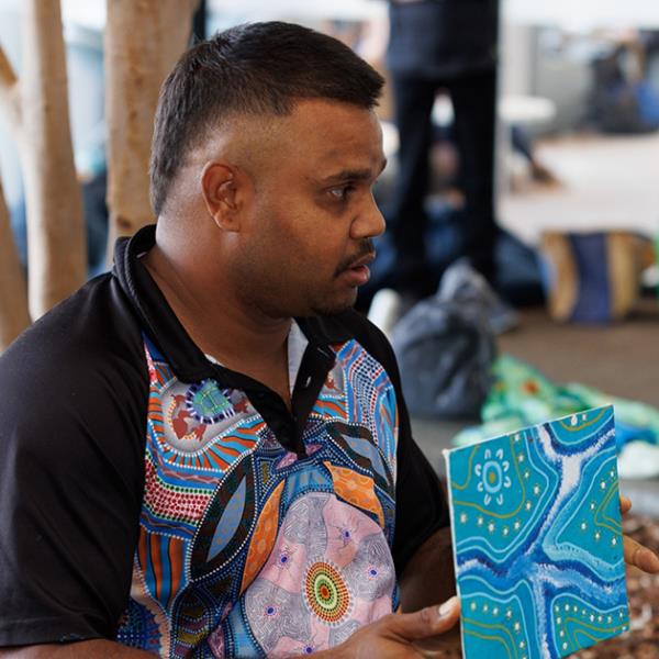 Justin Martin holding artwork from a traditional art workshop on Level four of the Library.