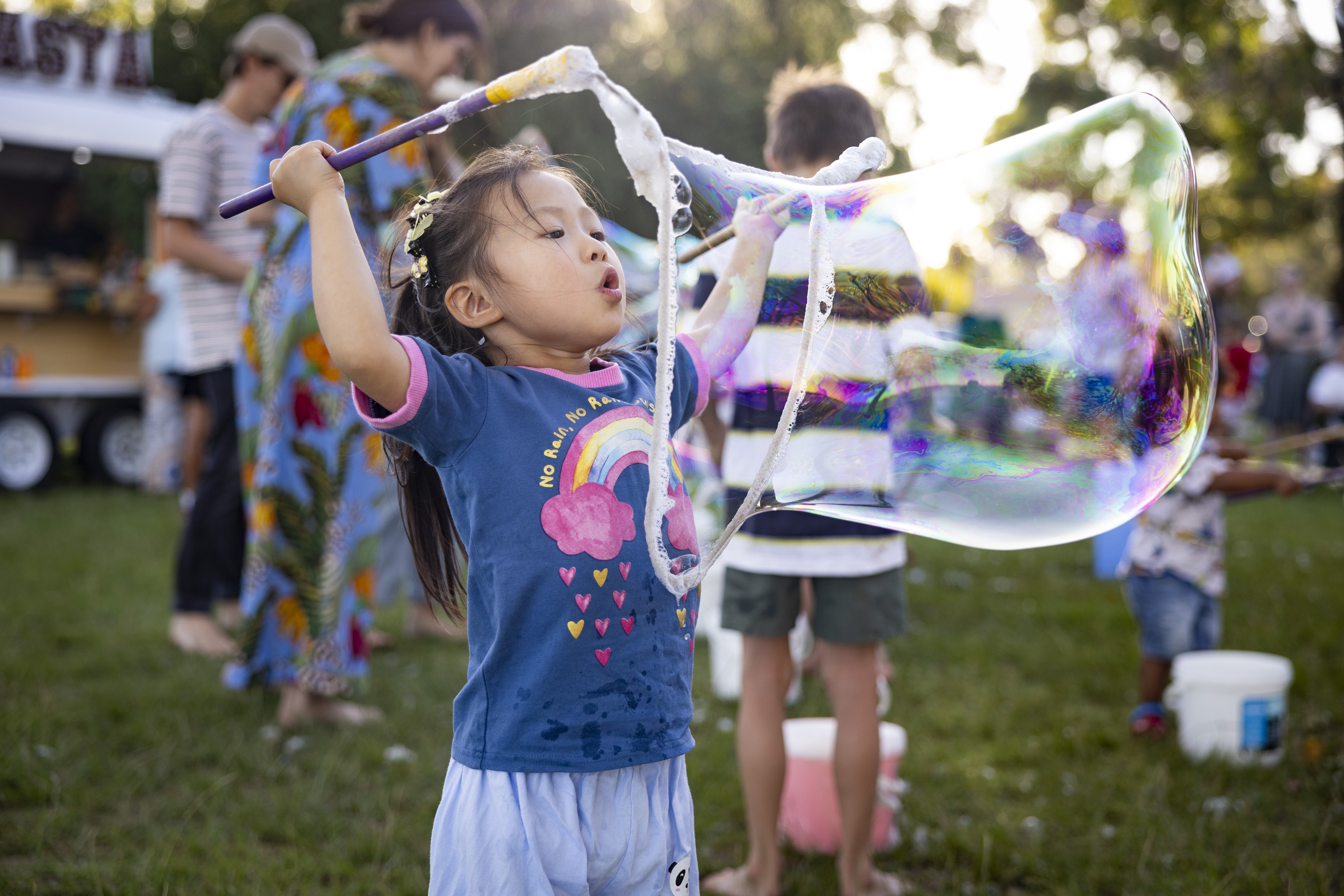 Child blowing a giant bubble at a community event