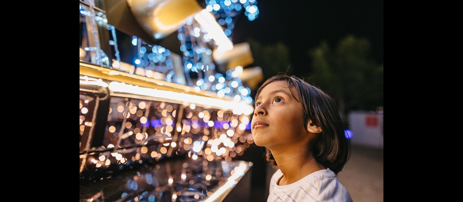 Child looking at Christmas Lights Trail installation 2023